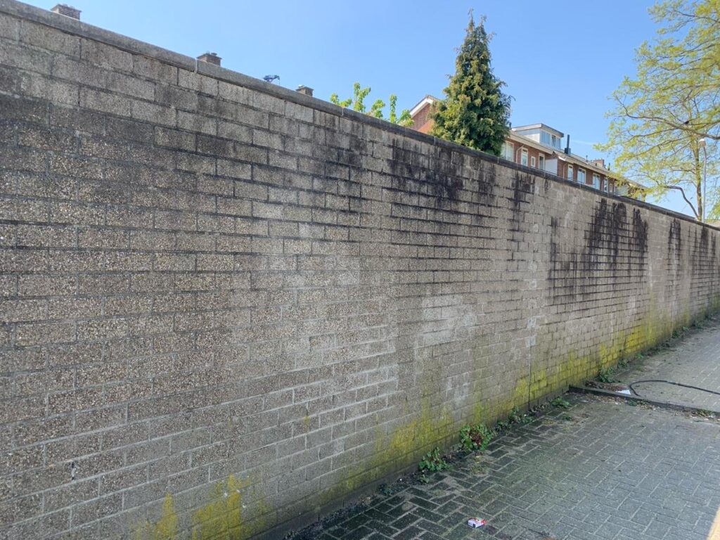 Betonnen muur met algen, mos en zwarte aanslag voor de reiniging