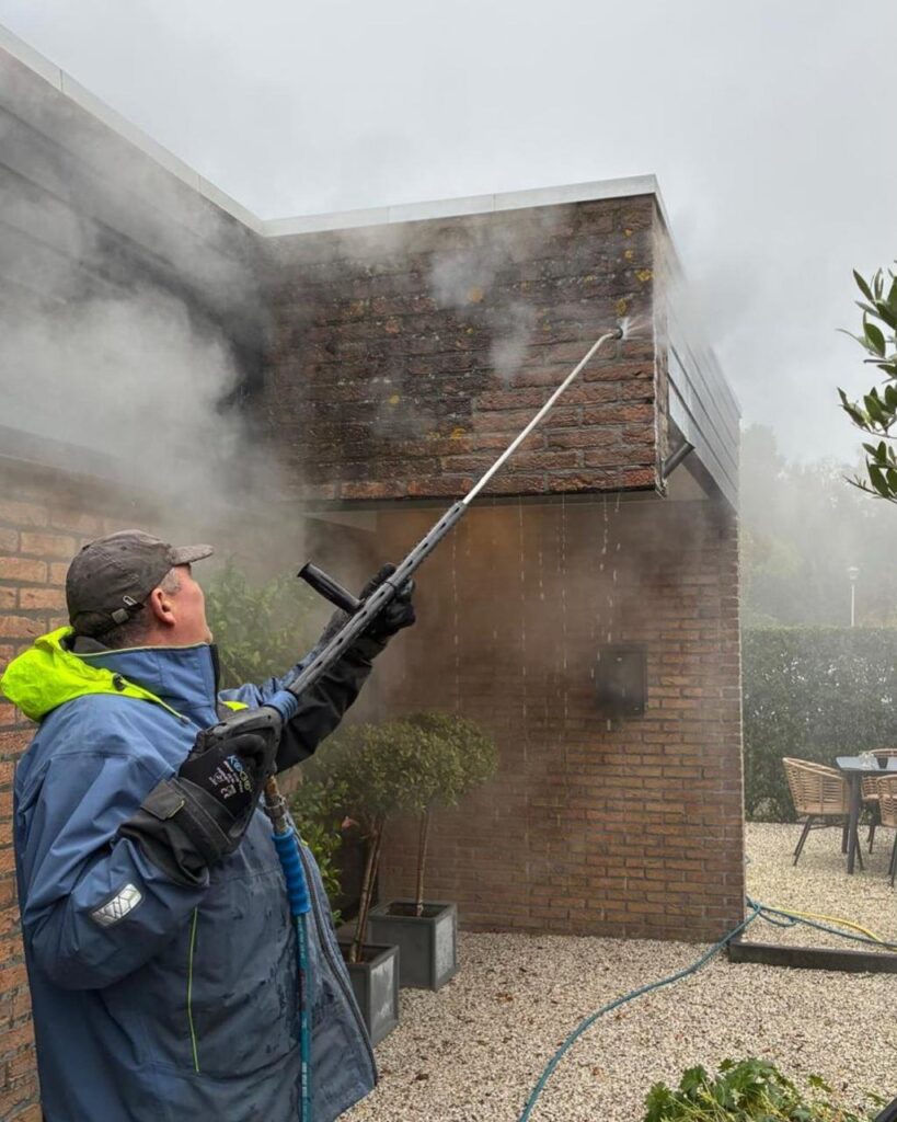 Bakstenen gevel wordt met heet water en stoom gereinigd